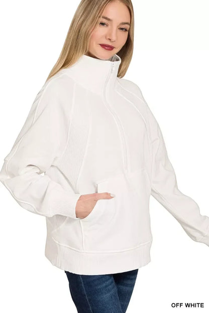 Woman wearing an off-white half-zip pullover sweater with front pocket and high collar