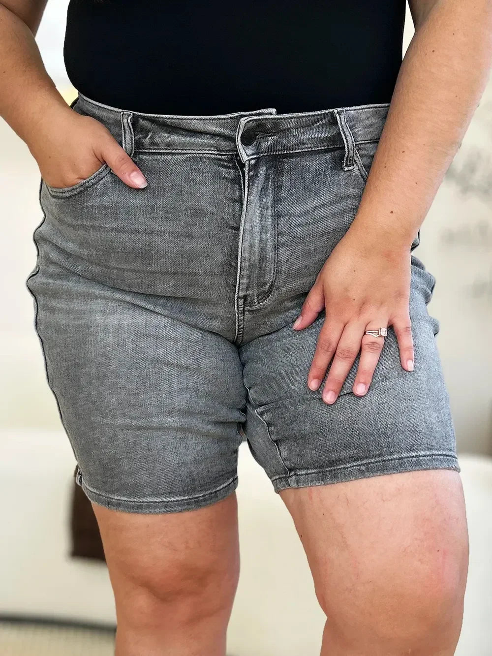 Close-up of woman wearing high-waisted gray denim shorts and black top