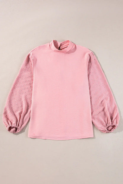 Light pink long sleeve blouse with textured mesh sleeves and high neckline on neutral background