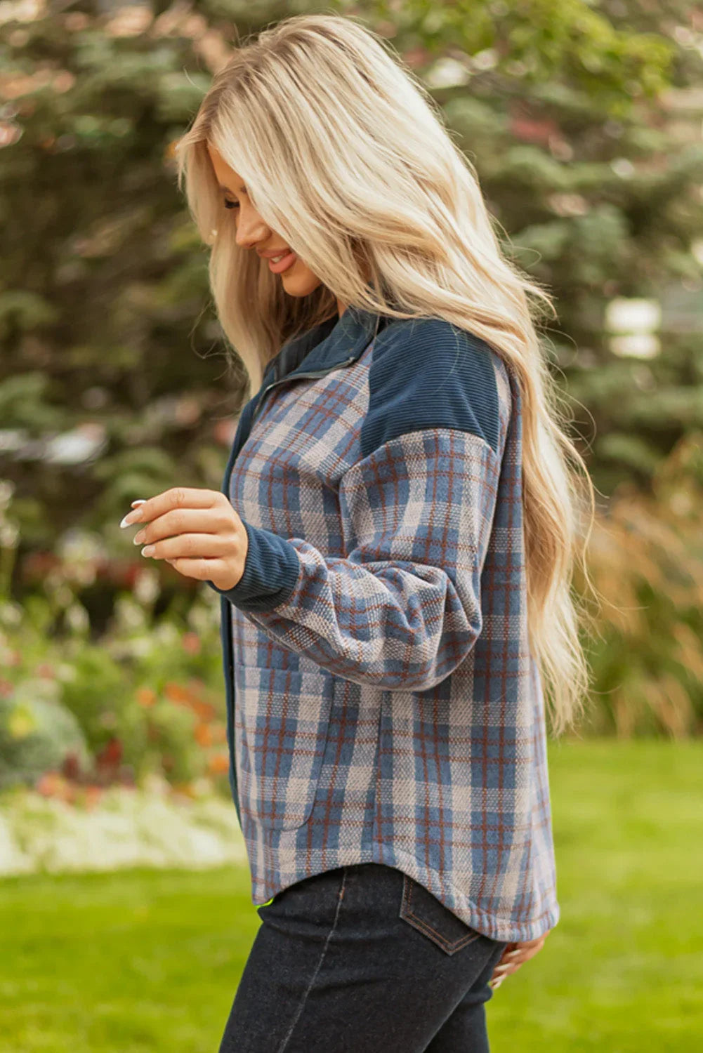 Woman outdoors wearing a blue plaid button-up shirt with long sleeves and dark jeans