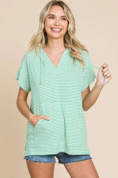 Woman wearing green and white striped hooded top with short sleeves and denim shorts
