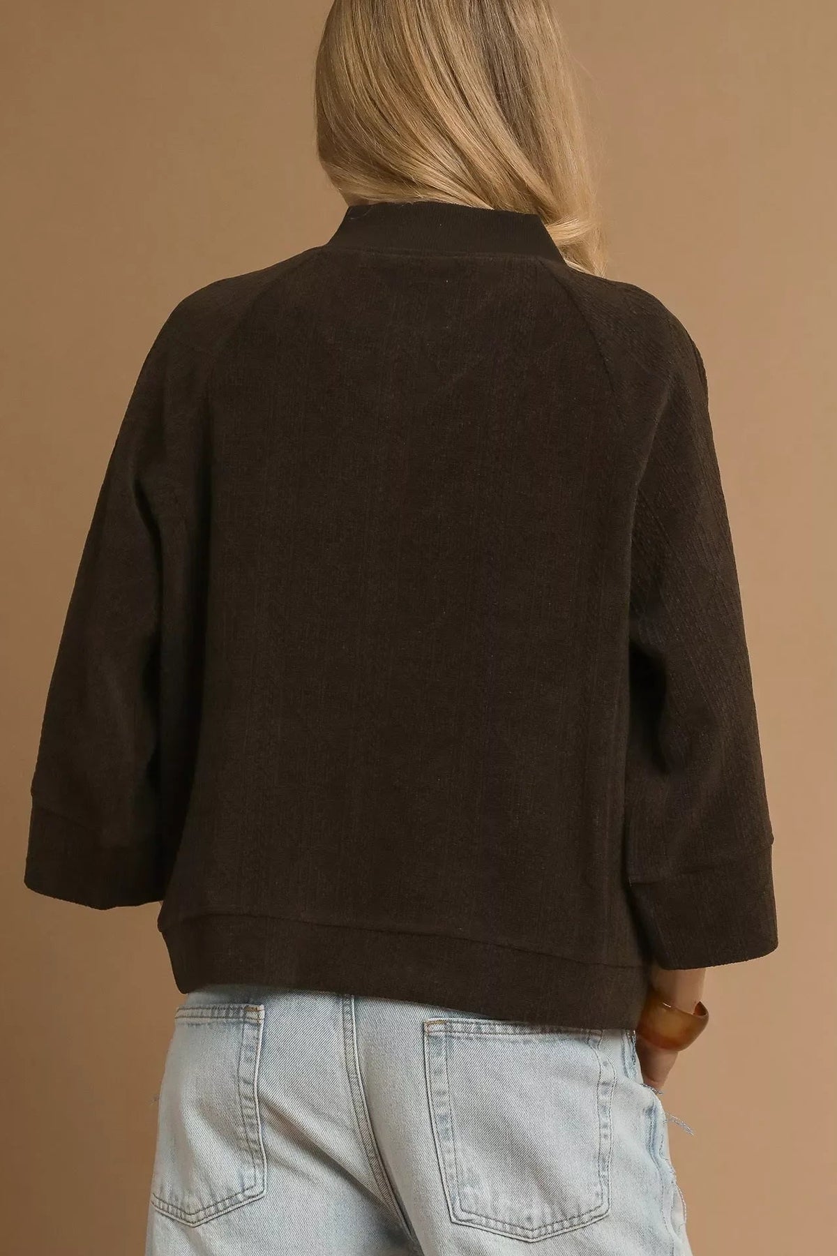 Back view of woman in chocolate brown relaxed jacket and light wash jeans