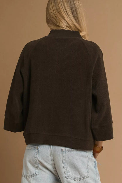 Back view of woman in chocolate brown relaxed jacket and light wash jeans