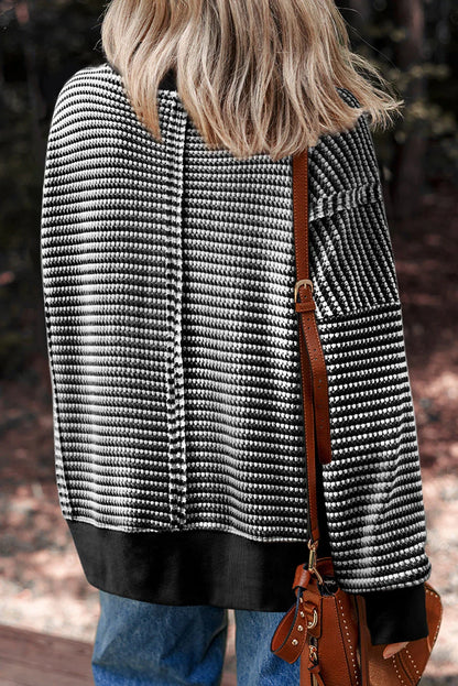 Woman wearing black and white striped knit sweater, blue jeans, and brown leather shoulder bag outdoors