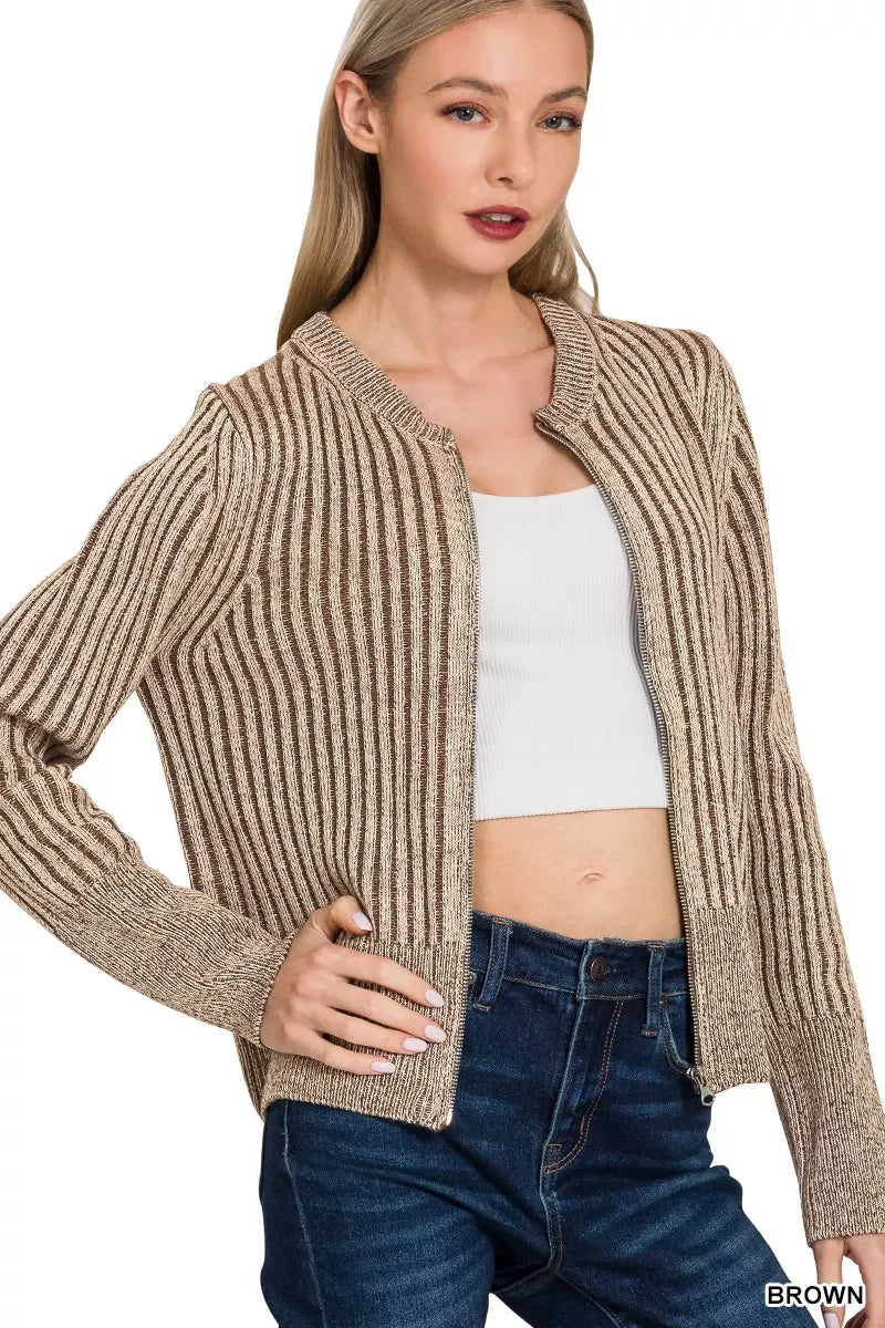 Woman wearing a brown ribbed knit cardigan, white crop top, and blue high-waisted jeans