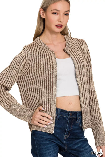 Woman wearing a brown ribbed knit cardigan, white crop top, and blue high-waisted jeans