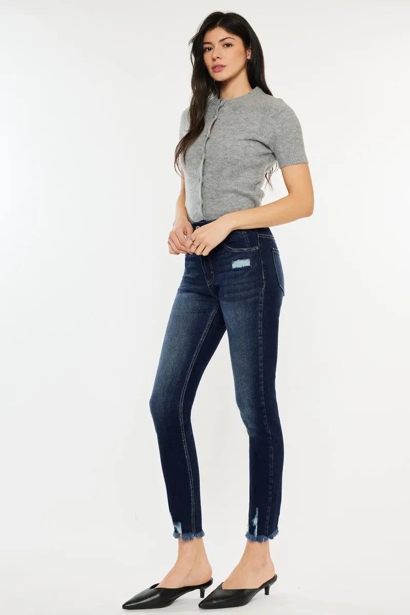 Woman wearing a grey short-sleeve knit top and dark wash skinny jeans with frayed hems