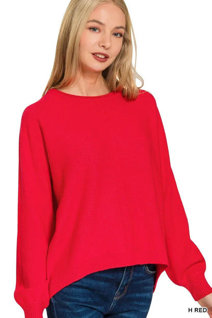 Woman wearing a relaxed fit, bright red sweater with long sleeves and blue jeans