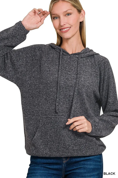 Woman wearing a charcoal knit hoodie with relaxed fit and front pocket, paired with jeans.