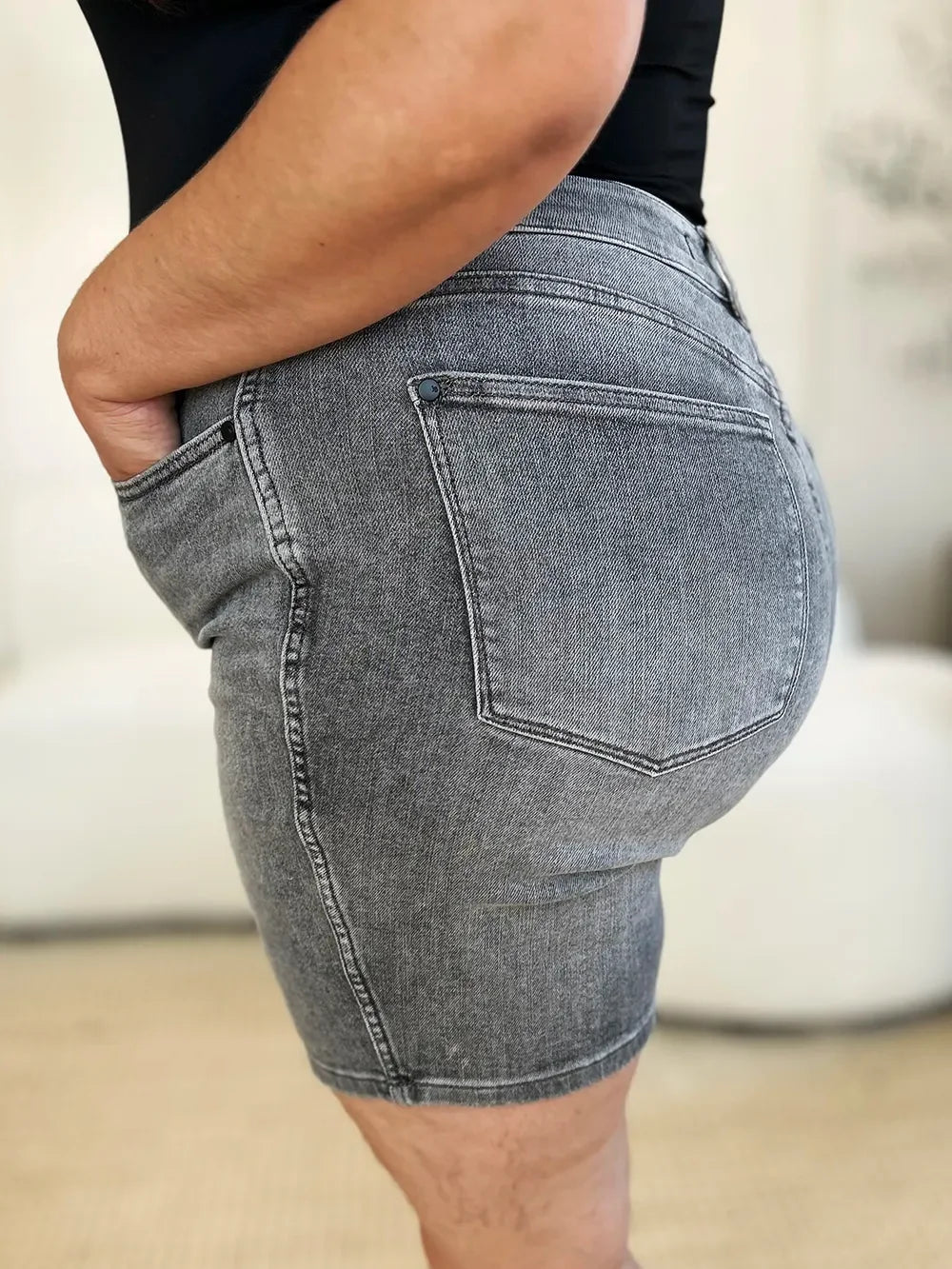 Close-up of a person wearing high-waisted gray denim shorts with side and back pockets