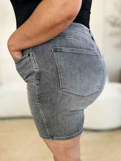 Close-up of a person wearing high-waisted gray denim shorts with side and back pockets