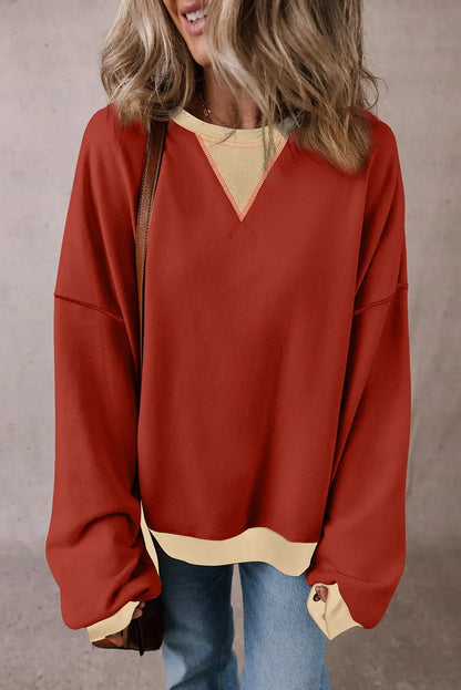 Woman wearing oversized red pullover sweater with beige trim and light blue jeans