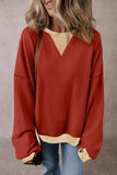 Woman wearing oversized red pullover sweater with beige trim and light blue jeans