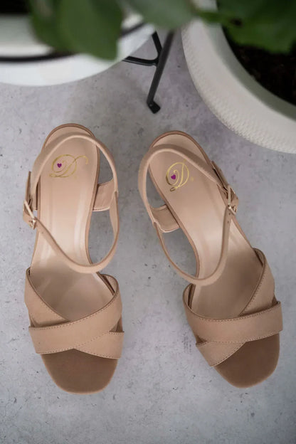 Beige strappy women's sandals with low heel on a light textured surface
