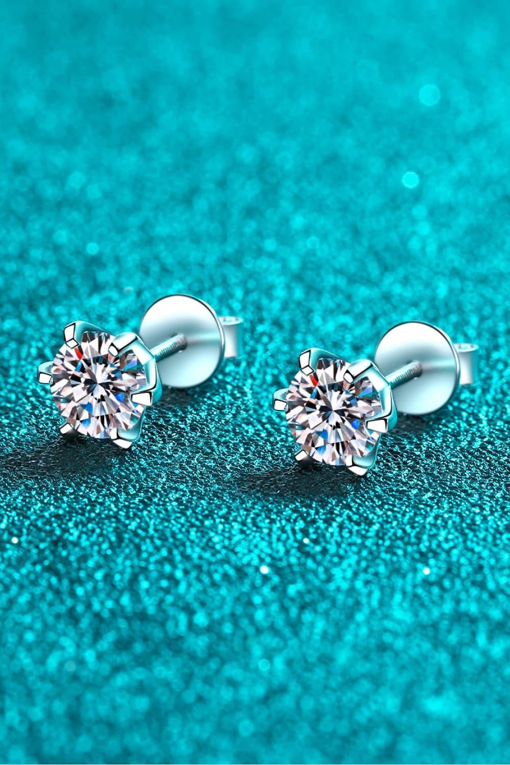 Silver round-cut stud earrings with clear gemstones on a sparkling turquoise background