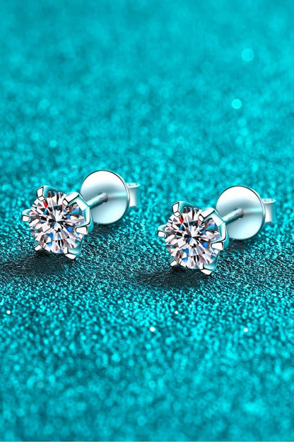 Silver round-cut stud earrings with clear gemstones on a sparkling turquoise background