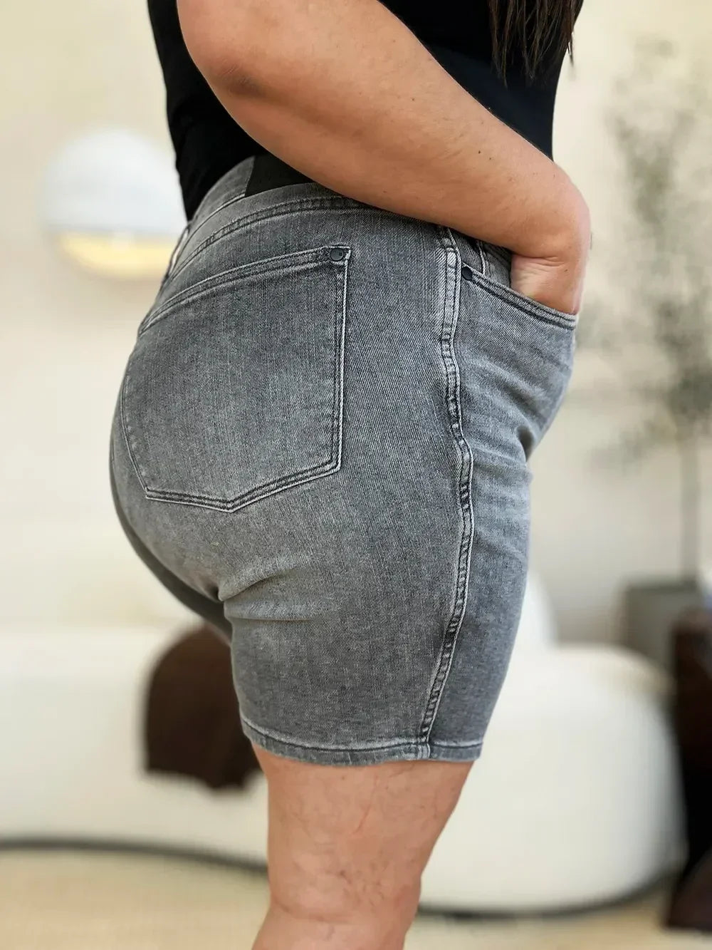 Woman wearing high-waisted grey denim shorts with a relaxed fit and visible back pocket