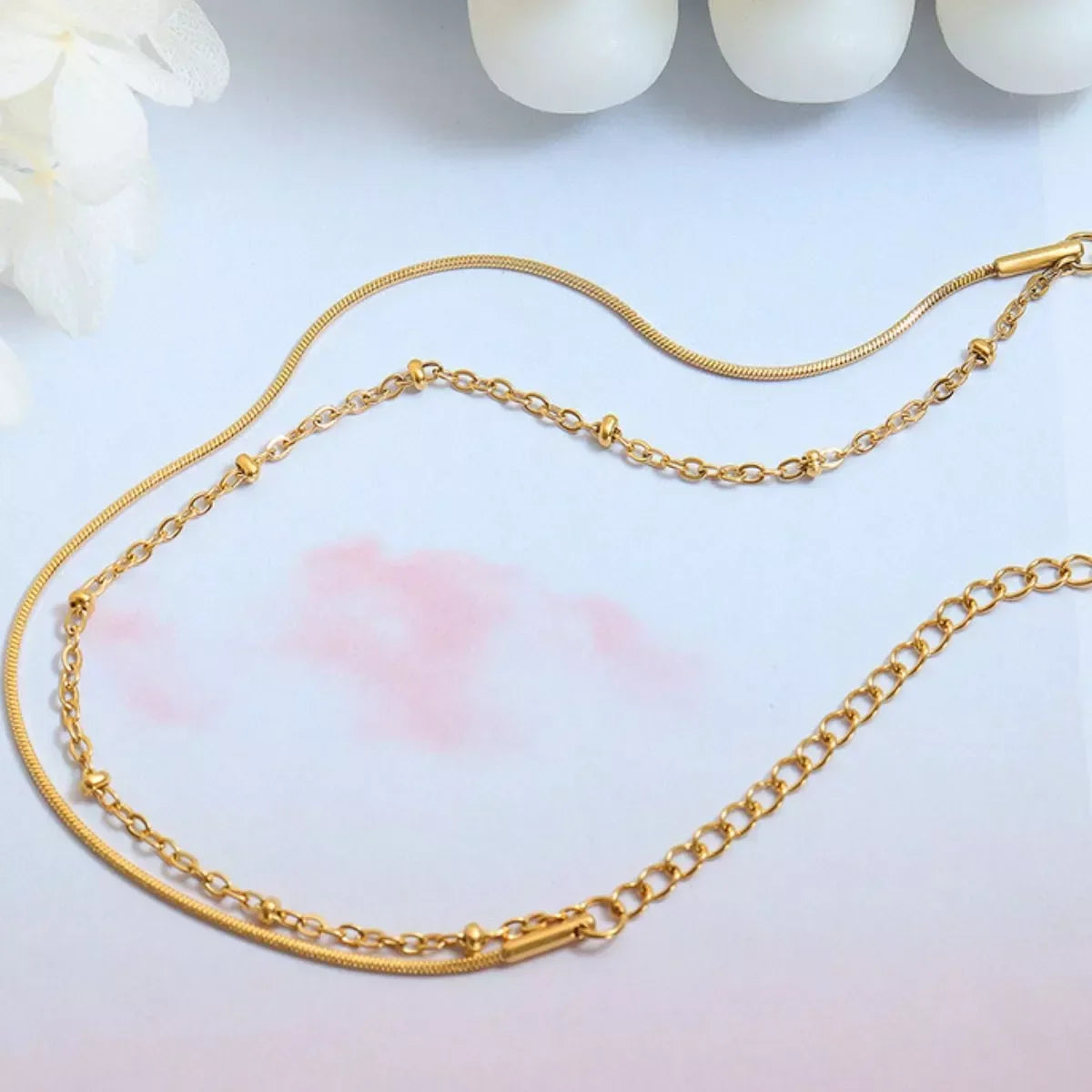 Delicate gold layered chain necklace with fine and textured links on a soft background