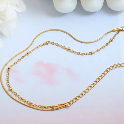 Delicate gold layered chain necklace with fine and textured links on a soft background