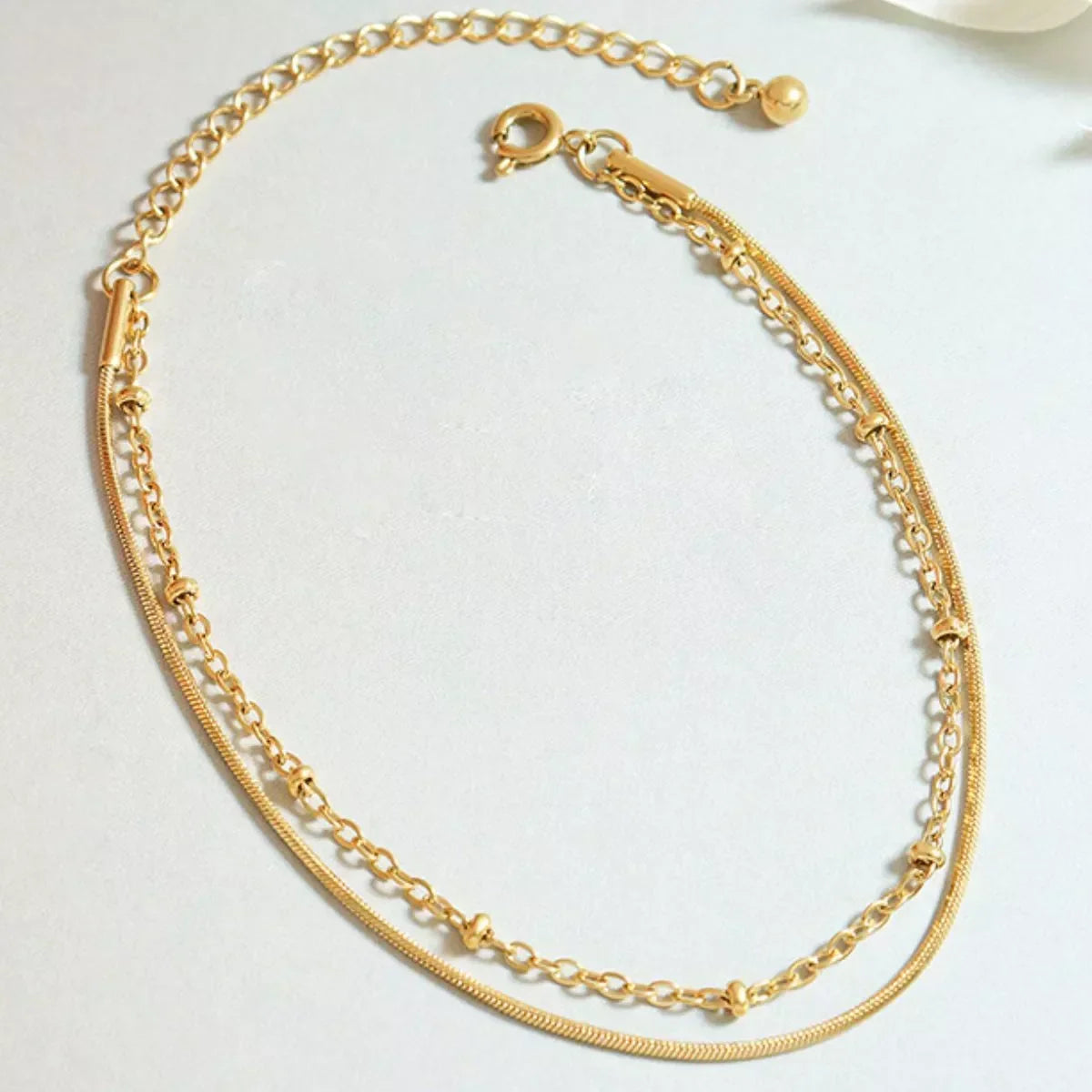 Gold layered chain bracelet with adjustable clasp on light background