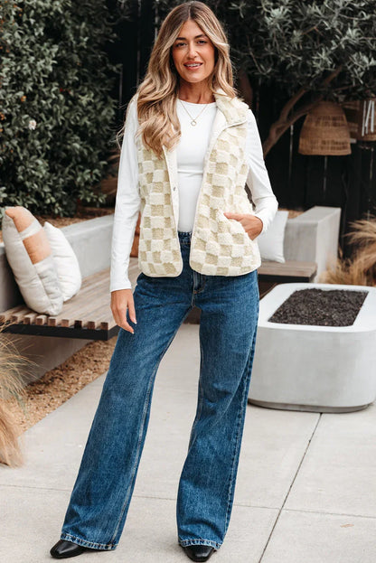 Woman wearing a cream checkered sherpa vest, white long sleeve top, and wide-leg jeans outdoors