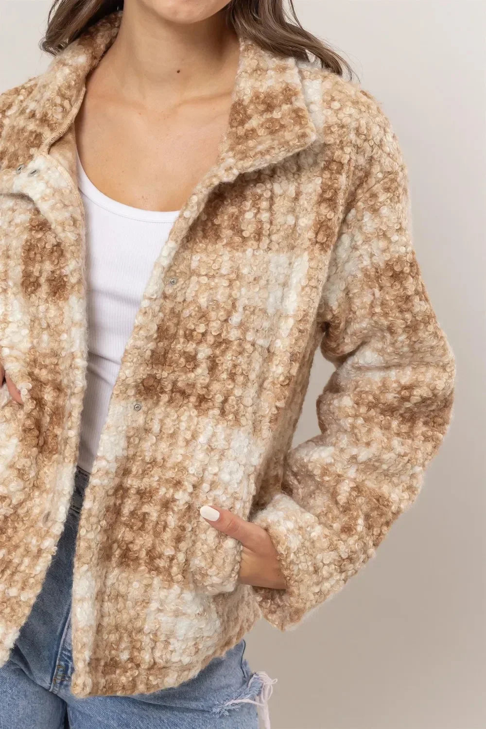 Woman wearing a beige and white checkered textured jacket with front pockets