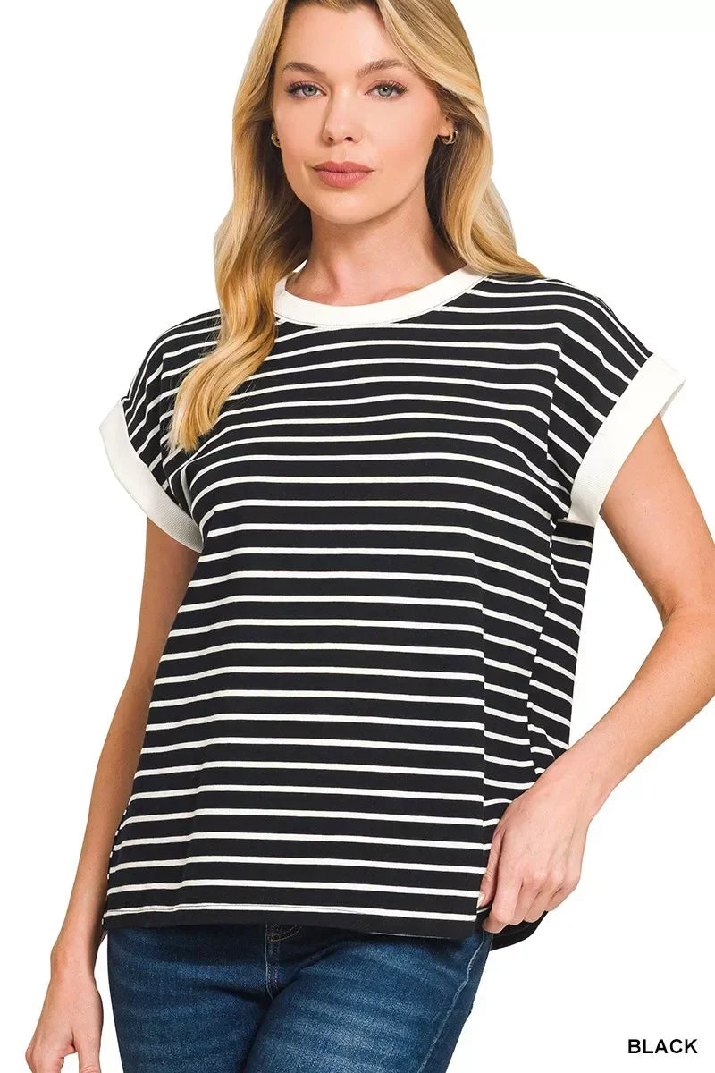Woman wearing a black and white striped short sleeve top with white trim and blue jeans.