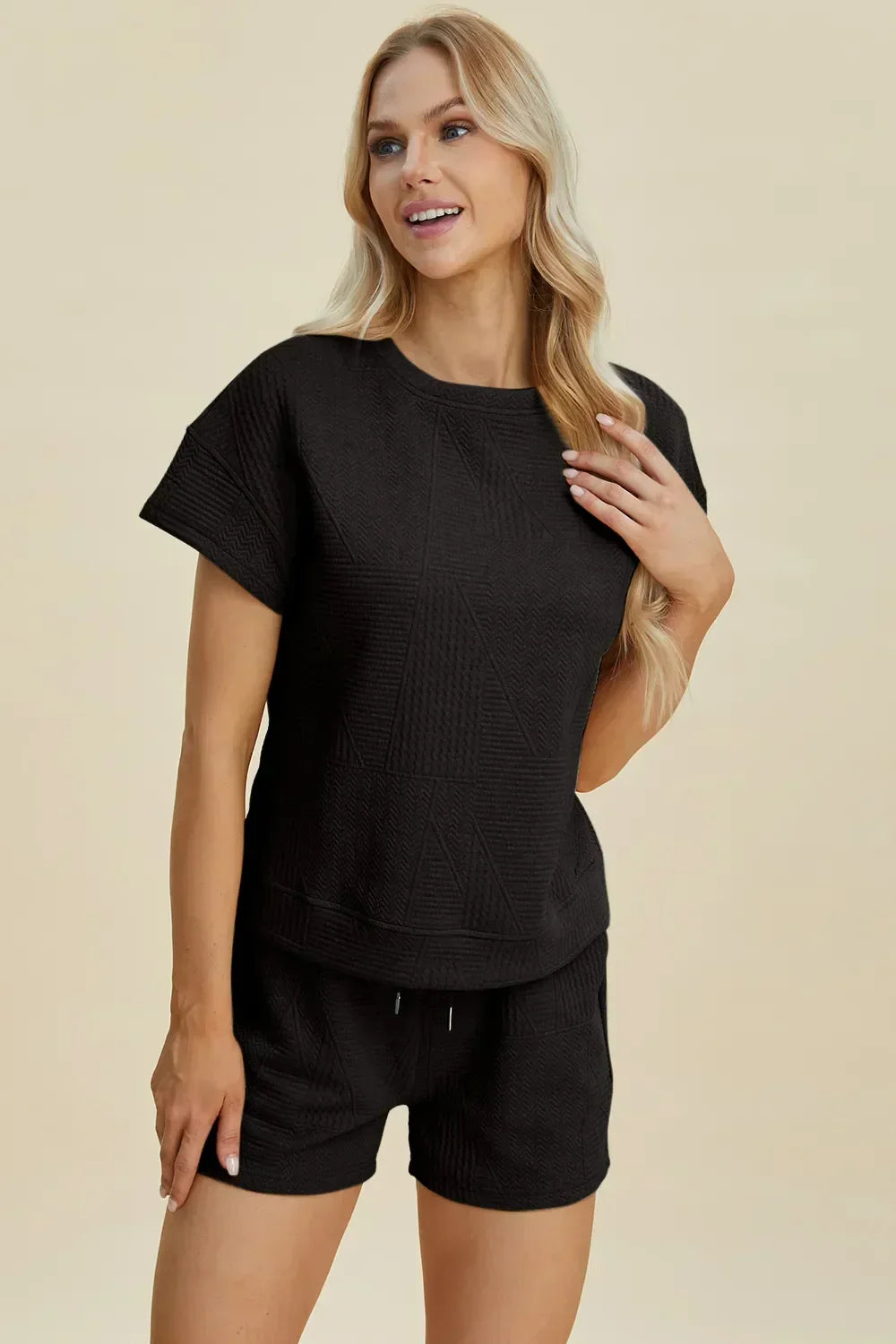 Woman wearing a black textured short-sleeve lounge set with relaxed fit shorts