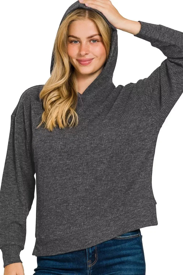 Woman wearing a dark grey ribbed hooded sweater with relaxed fit and blue jeans