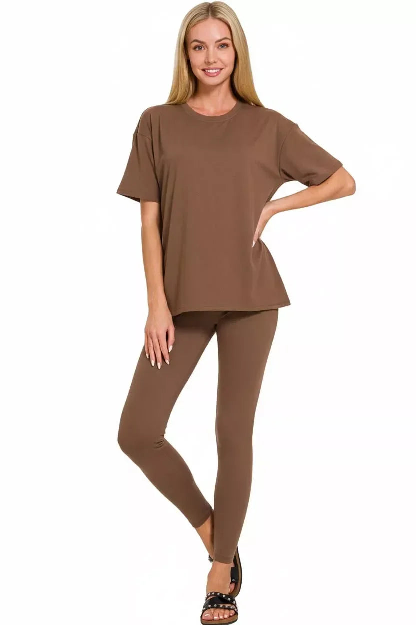 Woman wearing a brown relaxed-fit t-shirt and matching leggings, black sandals, on white background