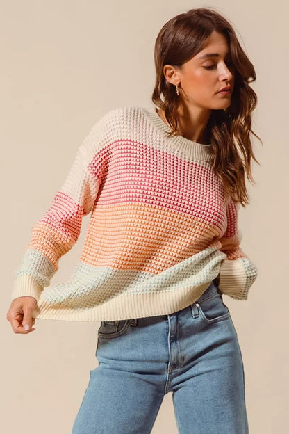 Woman wearing a pastel striped knit sweater and light blue high-waisted jeans