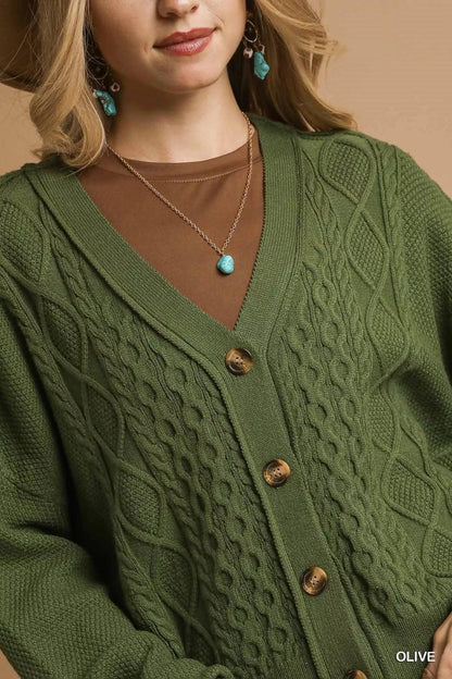 Woman wearing olive green cable knit cardigan with brown undershirt and turquoise jewelry.