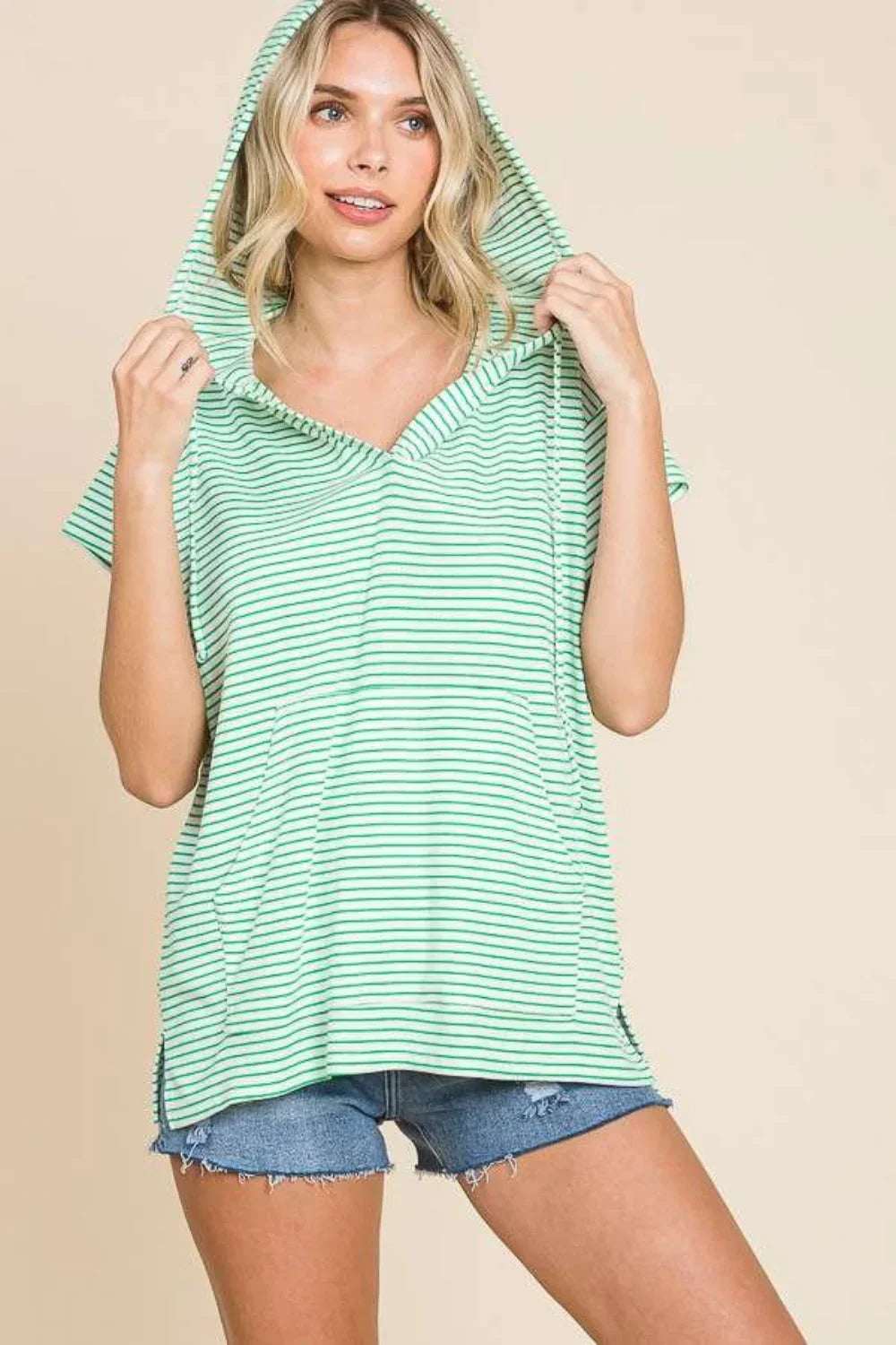 Woman in a mint green striped hooded top and denim shorts, casual relaxed style