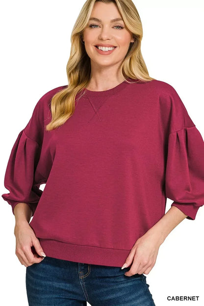 Woman wearing cabernet balloon sleeve pullover top paired with blue jeans