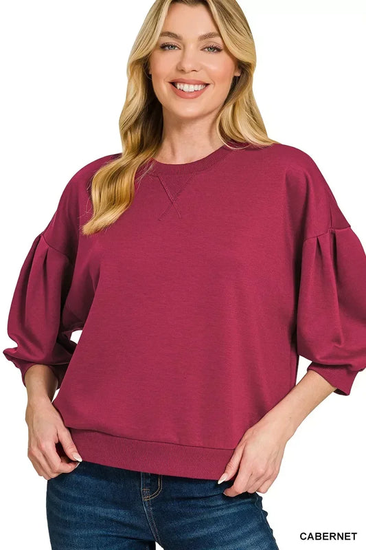 Woman wearing cabernet balloon sleeve pullover top paired with blue jeans