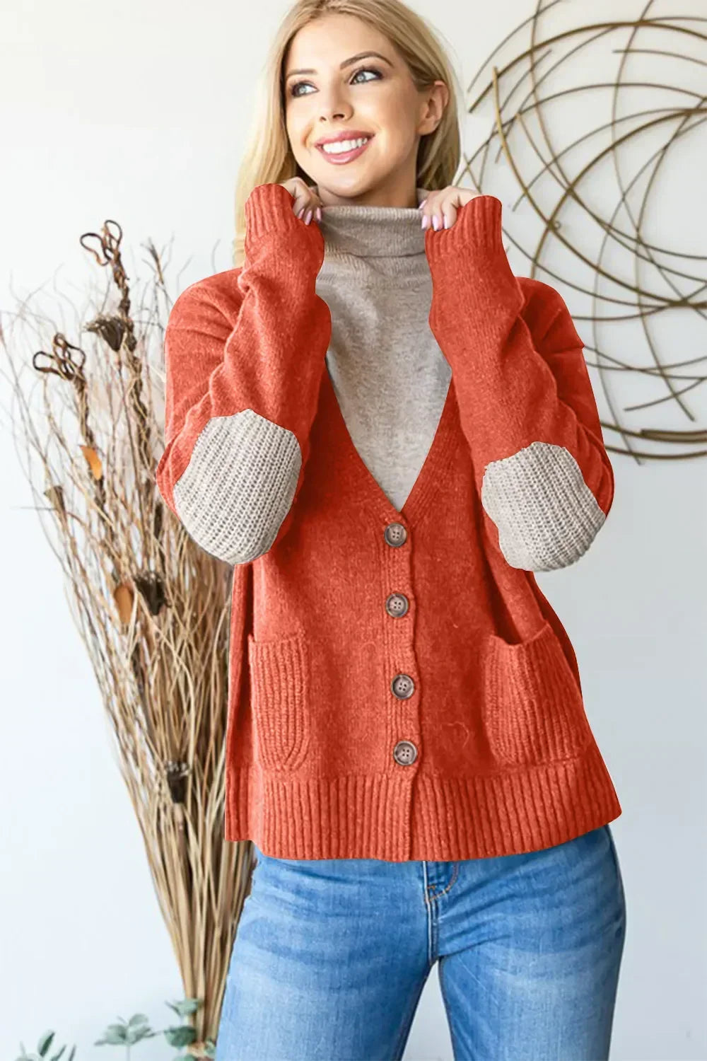 Woman in rust-colored button-front cardigan with beige elbow patches and turtleneck, casual style