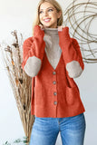 Woman in rust-colored button-front cardigan with beige elbow patches and turtleneck, casual style