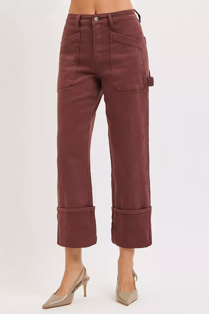 High-waisted brown wide-leg pants with large front pockets and cuffed hems, styled with heels