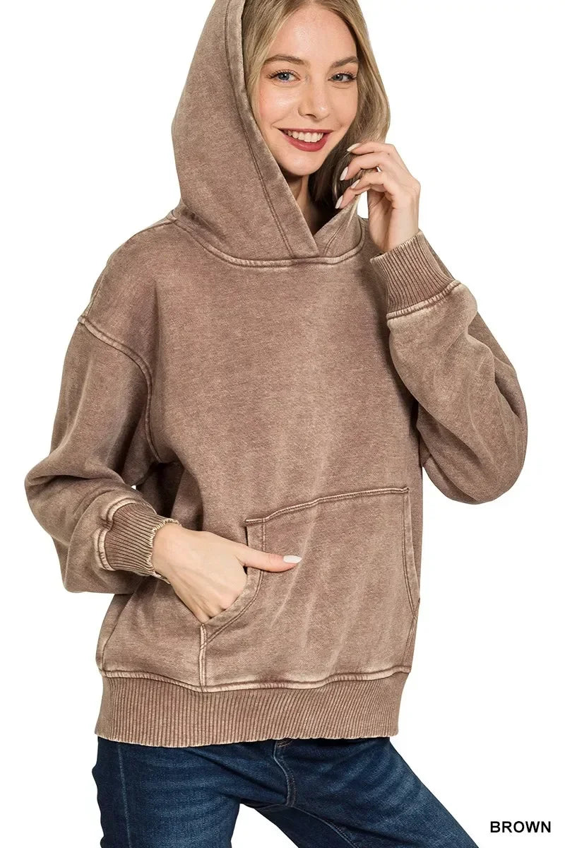 Woman wearing a relaxed-fit brown hoodie with a kangaroo pocket and blue jeans