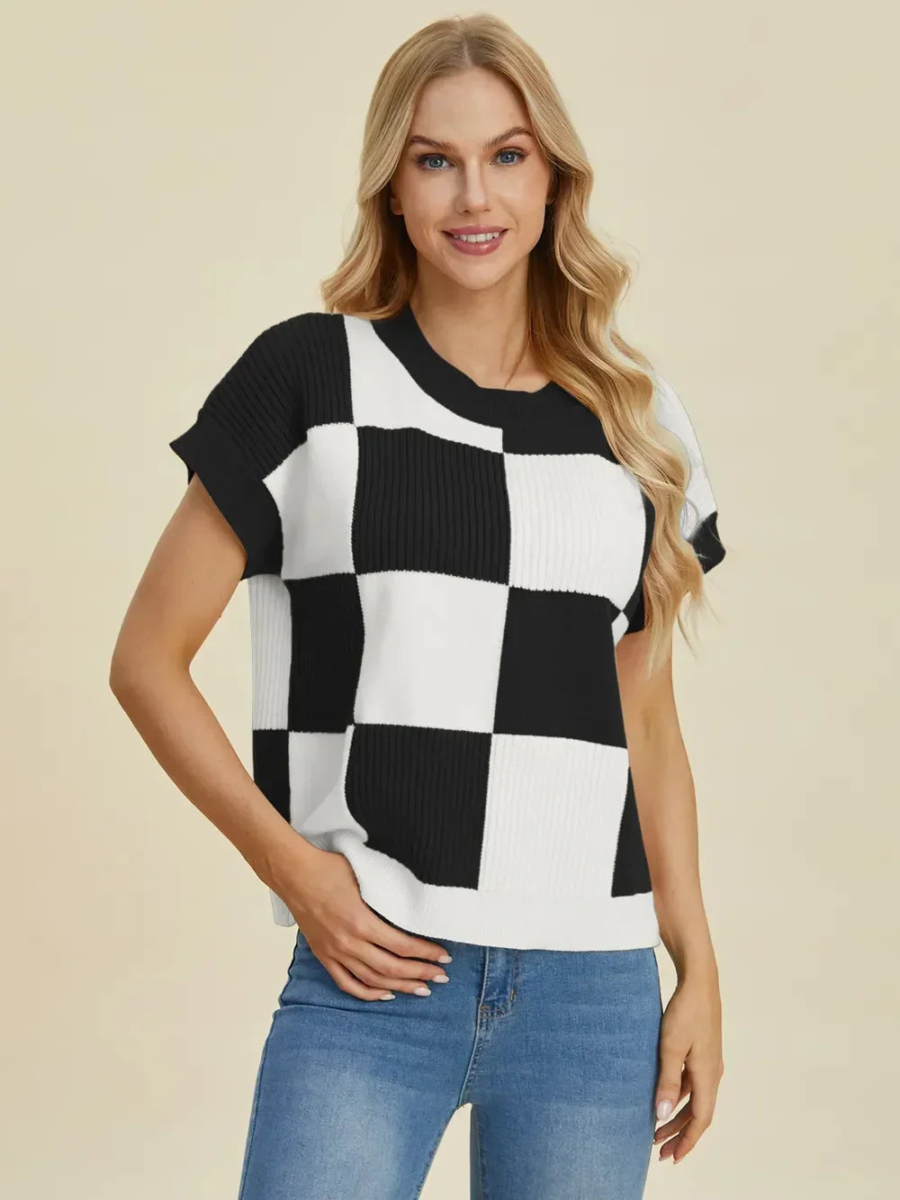 Woman wearing black and white checkered knit top with short sleeves and blue jeans