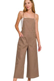 Woman wearing wide-leg brown overalls with square neckline and side buttons
