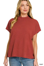Woman wearing a rust short sleeve mock neck textured top with relaxed fit and blue jeans