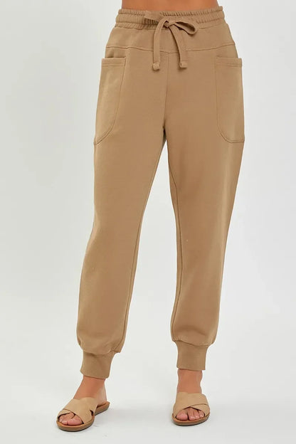 Women’s tan jogger pants with drawstring waist and front pockets, styled with sandals