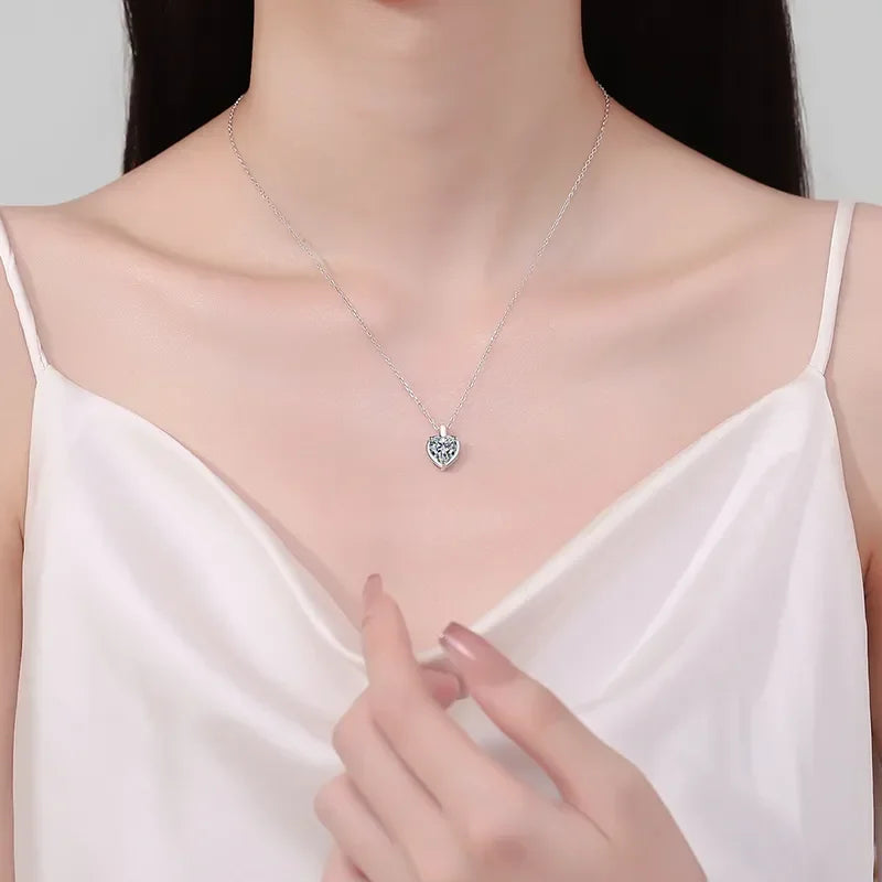 Woman in white camisole displaying a silver heart pendant necklace, elegant jewelry