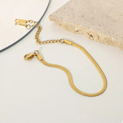 Gold herringbone chain bracelet with adjustable clasp on neutral background