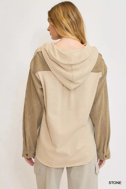 Back view of woman wearing beige hooded jacket with textured long sleeves and cargo pants