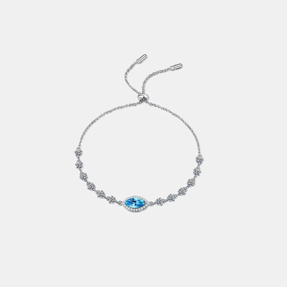 Delicate silver bracelet with blue marquise gemstone and floral crystal accents on white background