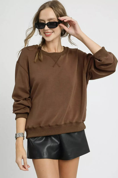 Woman wearing mocha brown oversized sweatshirt with black faux leather shorts and sunglasses