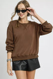 Woman wearing mocha brown oversized sweatshirt with black faux leather shorts and sunglasses