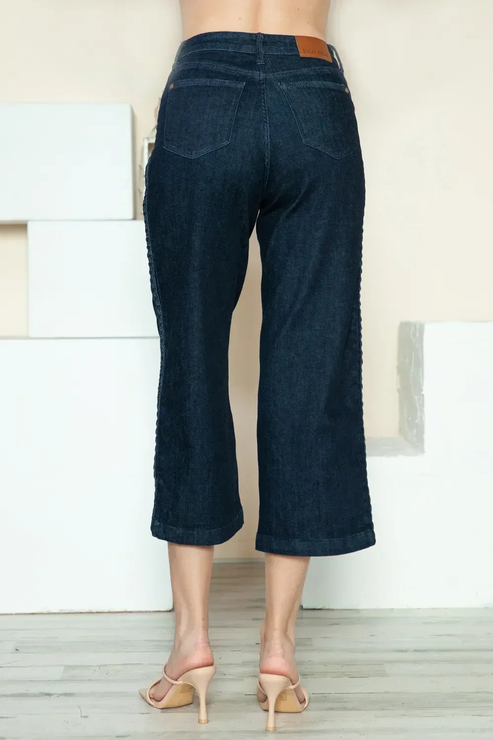 Back view of woman wearing dark wash wide-leg cropped jeans and nude heels